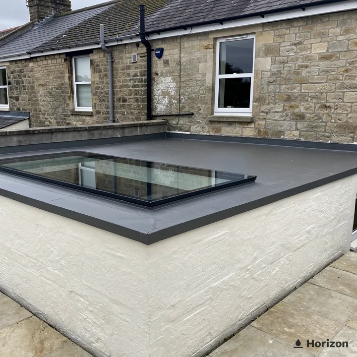 Flat rooflight on the roof of a white painted extension beside stone houses.