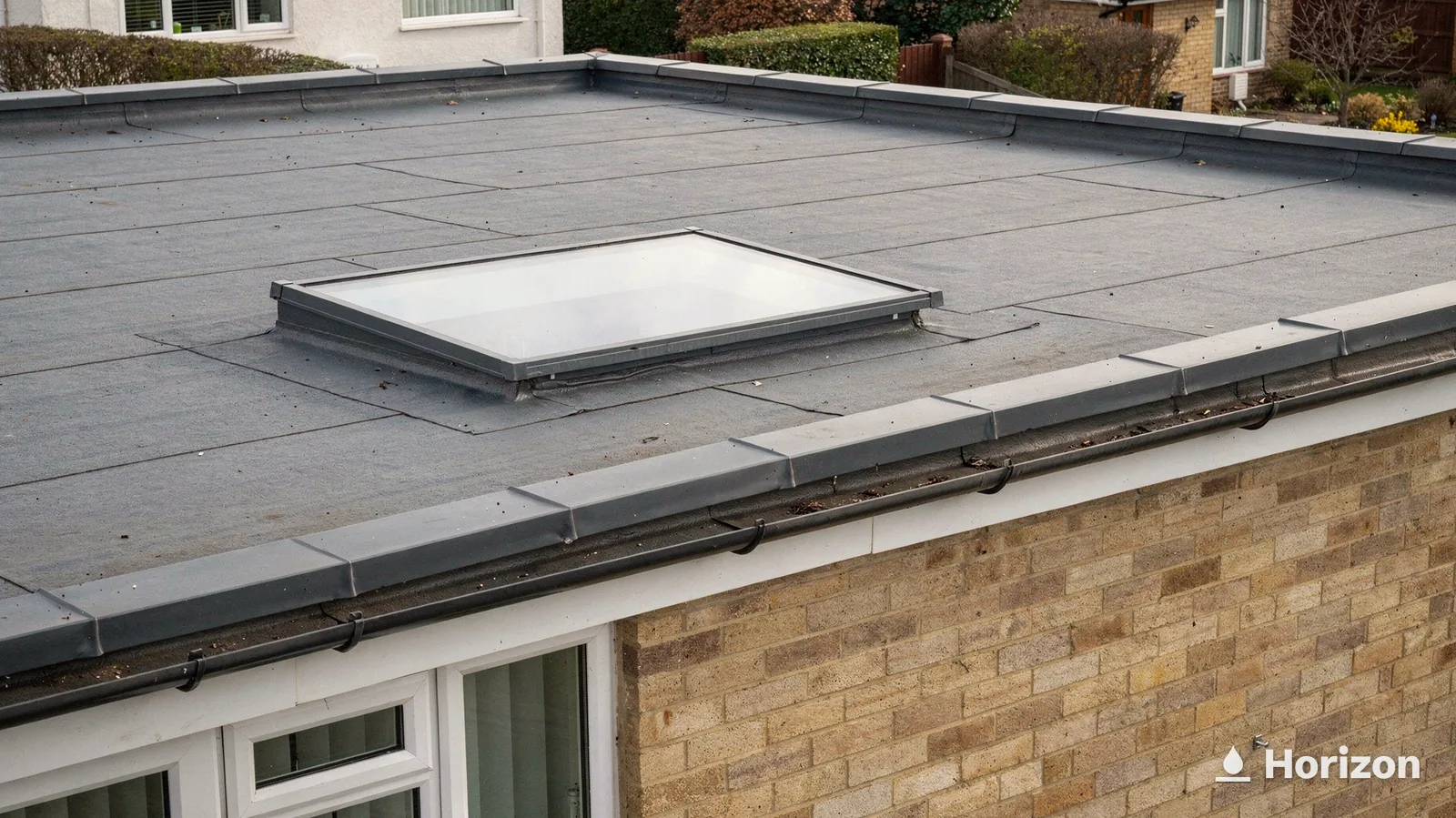 Fixed flat rooflight on a grey flat roof above a yellow brick extension.