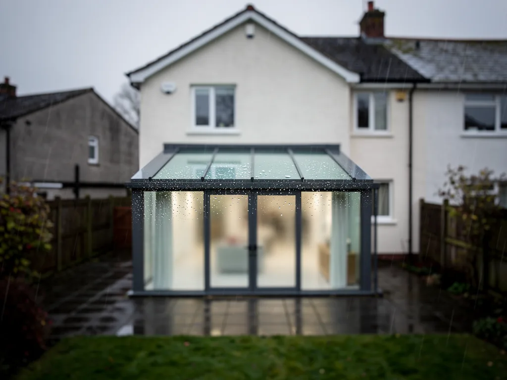 A roof lantern on a single-storey rear extension of a render semi, seen from the garden in light rain